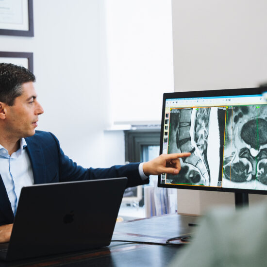 Surgeon reviewing spine MRI imaging on screen